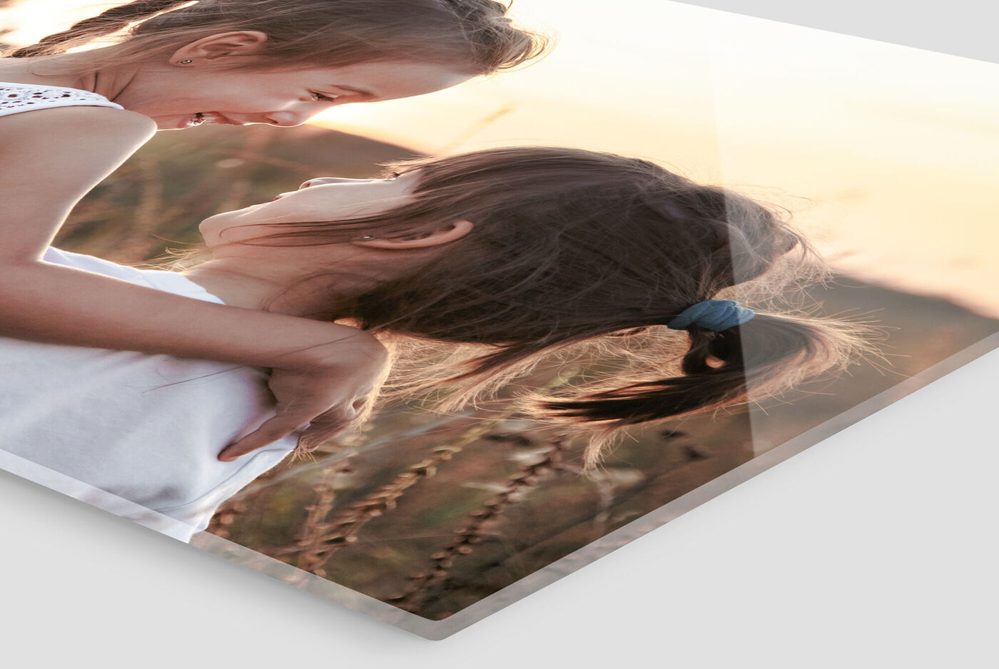 Two girls are standing in a meadow, smiling at each other as the sun sets