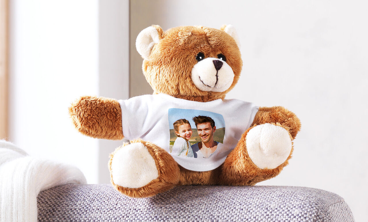 A cuddly teddy bear with a personalized T-shirt featuring a photo