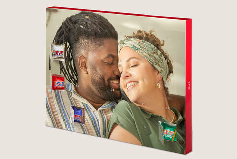 A couple smiles happily at each other, surrounded by colorful snacks and sweets in a loving environment.